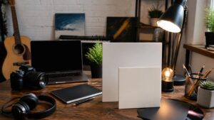 Budget-friendly musician artwork setup with blank album sleeve mockups, headphones, inexpensive light, camera, instruments, and blank laptop